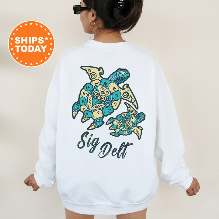 A woman wearing a white sweatshirt with a colorful graphic of a turtle and the text "Sign Delta" printed on it.