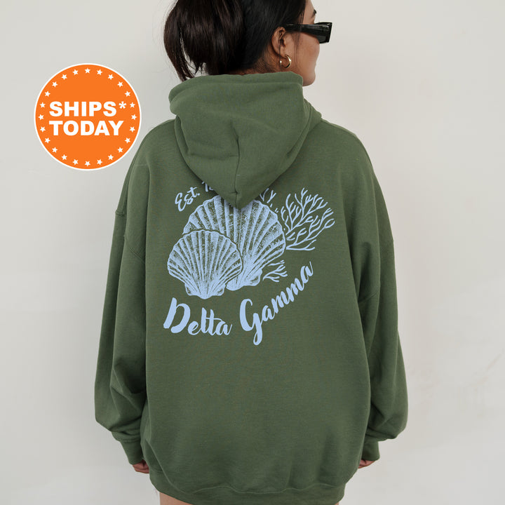 A person wearing a green hoodie with a graphic design of seashells and the text "Delta Gamma" printed on it.