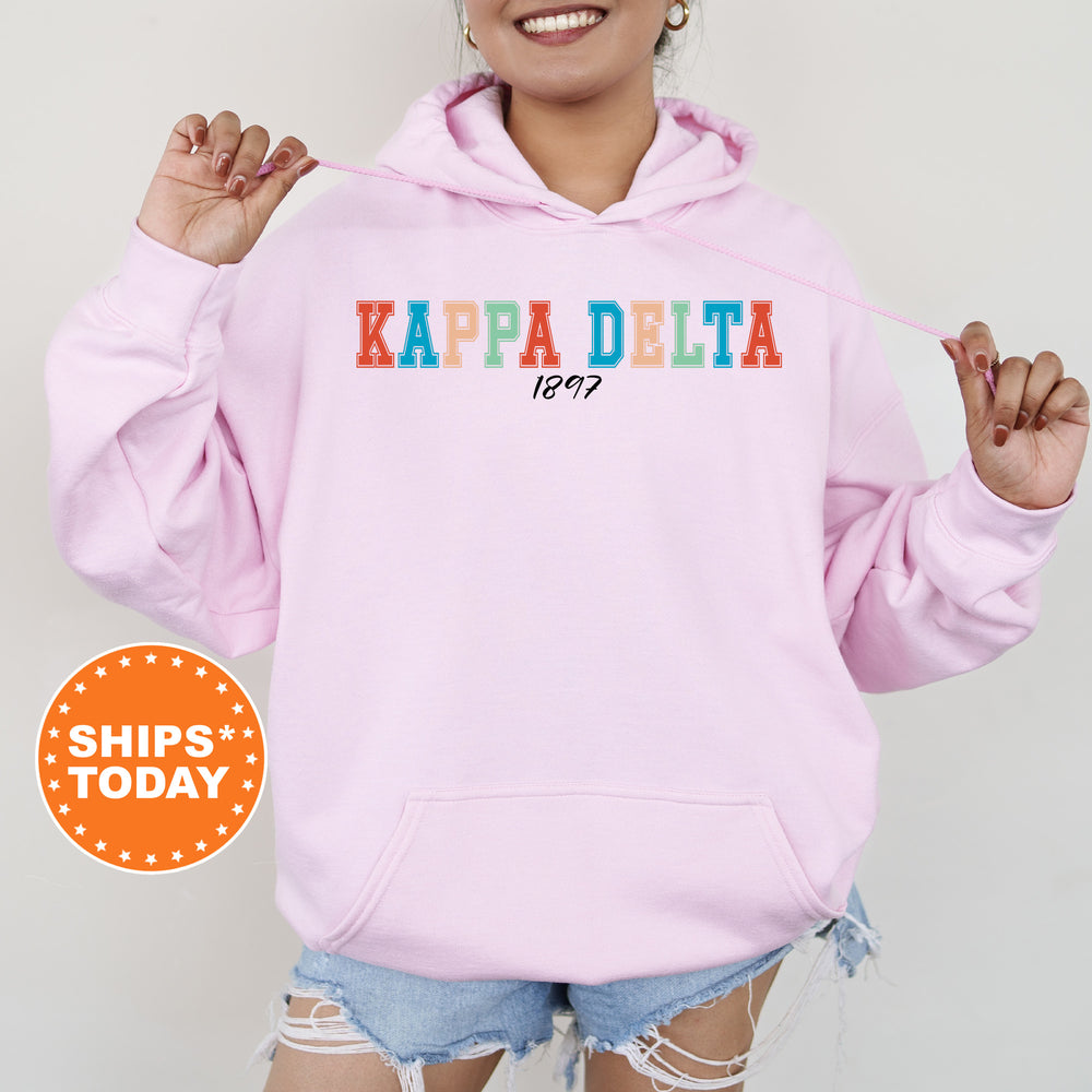 a woman wearing a pink kapa delta hoodie