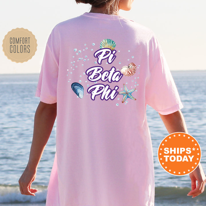 a woman wearing a pink pi beta phi shirt on the beach