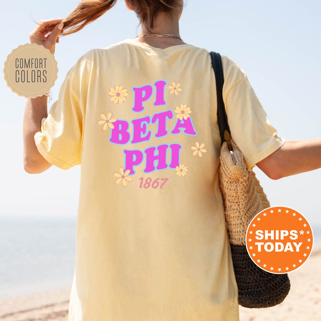 A person wearing a yellow t-shirt with the text "PI BETA PHI 1867" printed on it, standing on a beach with a handbag.