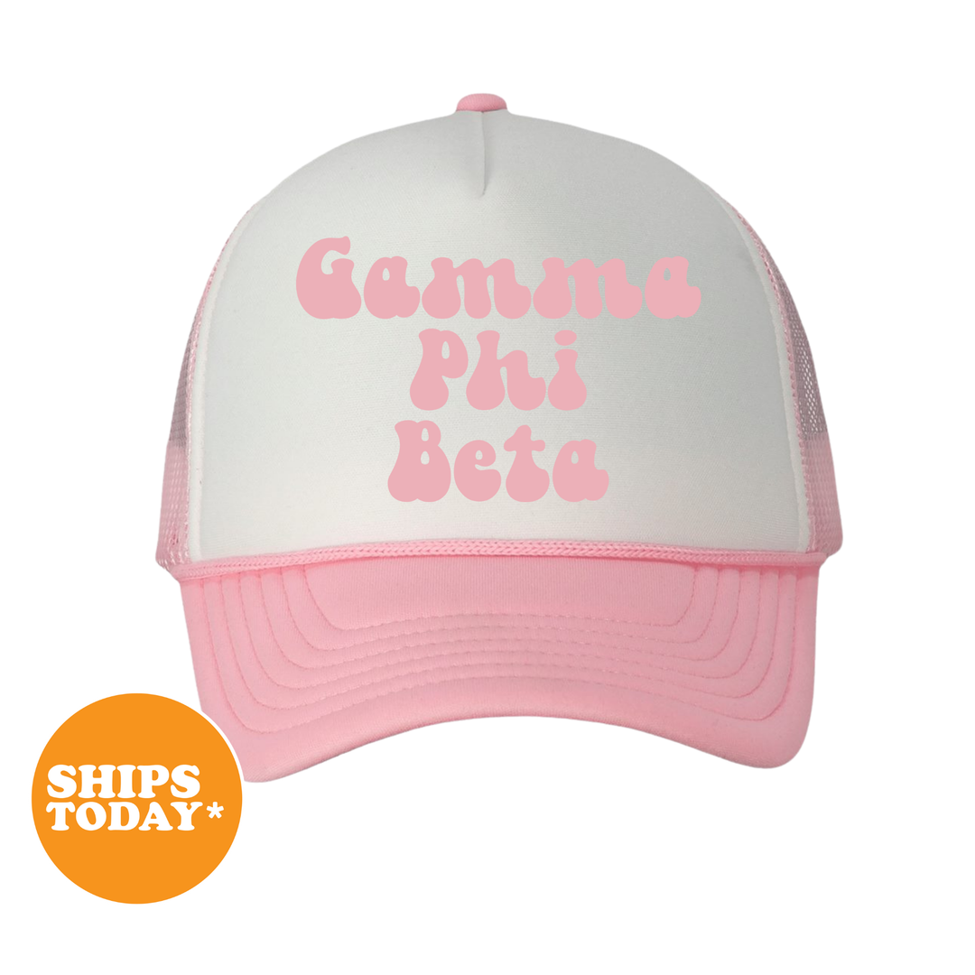 A pink and white baseball cap with the text "Gamma Phi Beta" printed on it.