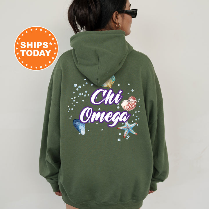 a woman wearing a green hoodie with the words chi omeg on it