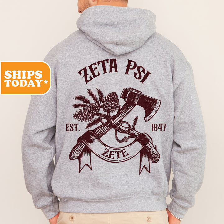 a man in a gray hoodie with a hammer and pine cone on it