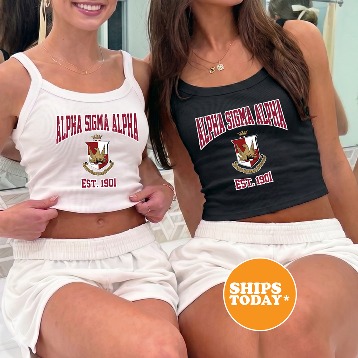 Two women wearing tank tops with the text "ALPA SIGMA ALPHA EST. 1901" are sitting next to each other.
