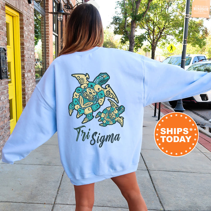 A woman wearing a light blue sweatshirt with a turtle design and text on the back, standing on a sidewalk.