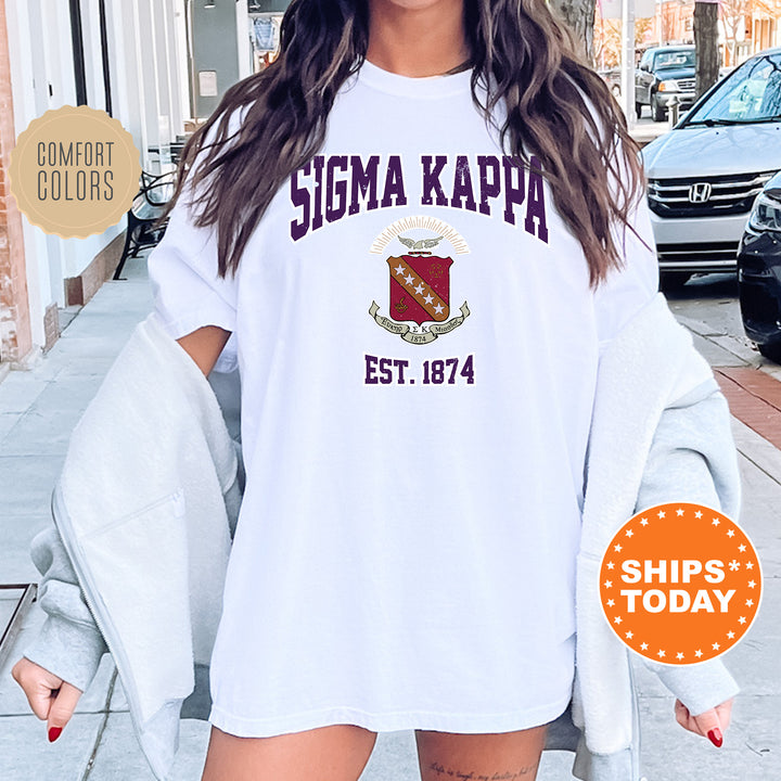 a woman wearing a white tshirt with a maroon and white logo on it