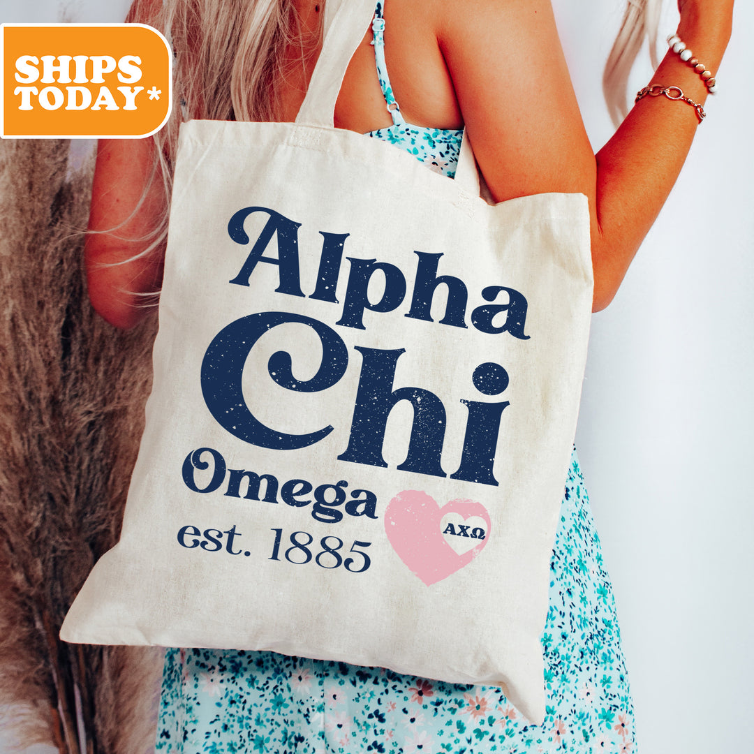 a woman holding a tote bag that says, alpha chi omega est