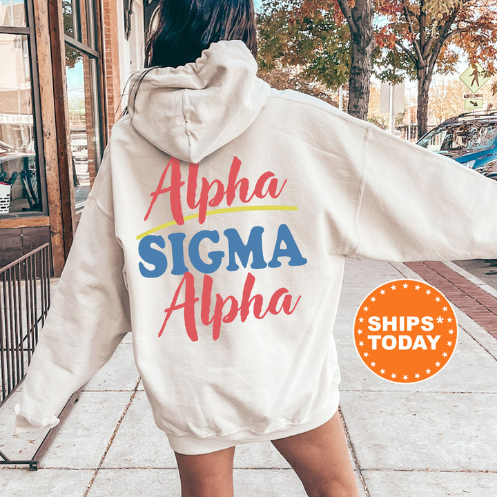 A person wearing a white hoodie with the text "Alpha Sigma Alpha" printed on it, standing on a sidewalk with trees and a building in the background.