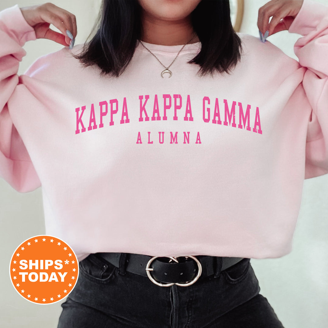a woman wearing a pink sweatshirt with the words kapa kapa gama on