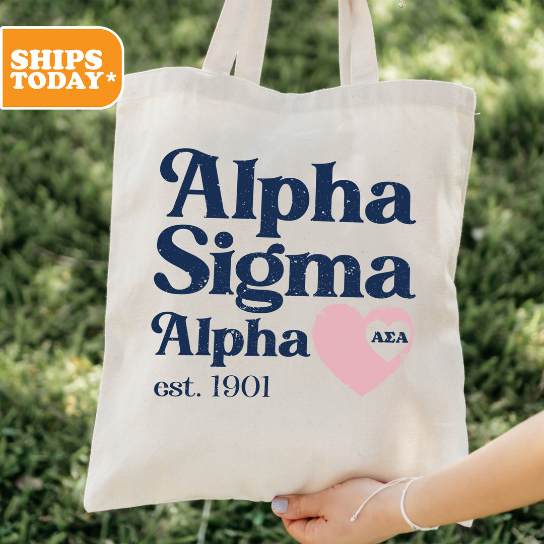 a person holding a tote bag that says, alpha signa alpha