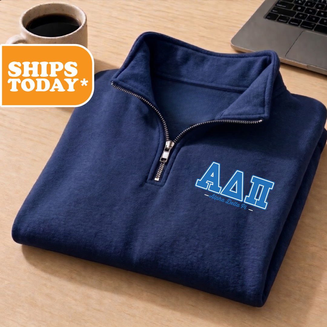 A navy blue zip-up jacket with the letters 'AA' printed on the left side, placed on a wooden surface next to a laptop and a coffee cup.