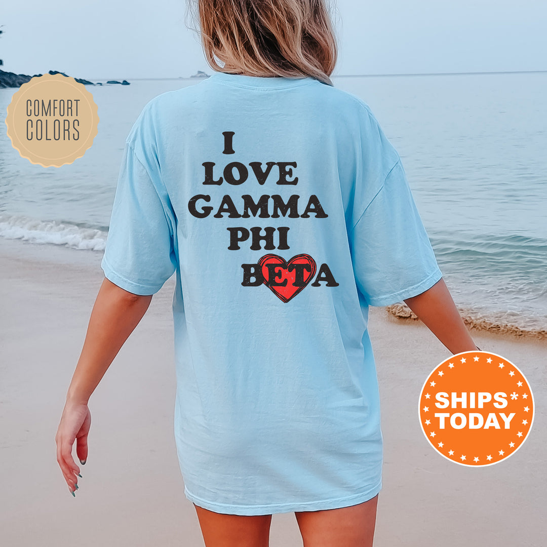 a woman walking on the beach wearing a shirt that says i love gama phi