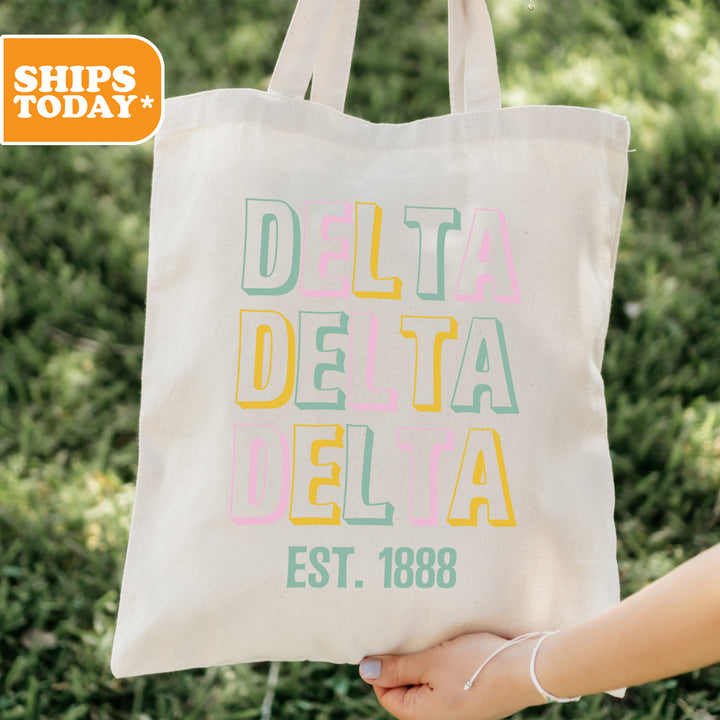 a person holding a tote bag that says delta delta delta