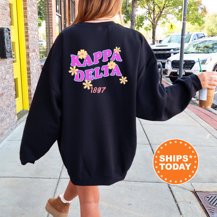 A person wearing a black sweatshirt with the text " Kappa Delta" printed on it, walking down a sidewalk.