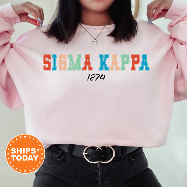 a woman wearing a pink sweatshirt with the word sigma kapa printed on it