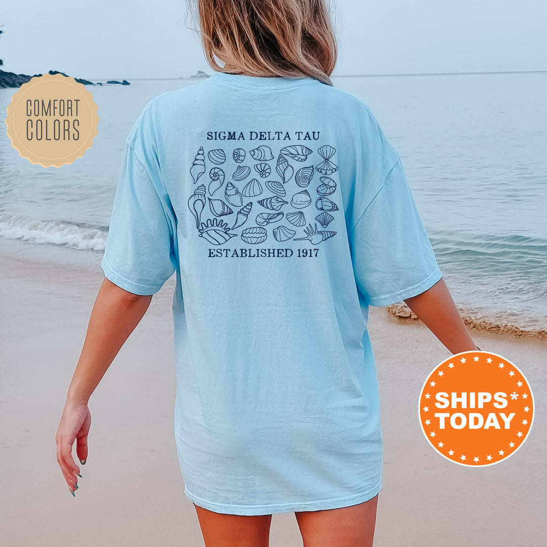 a woman walking on the beach wearing a blue shirt