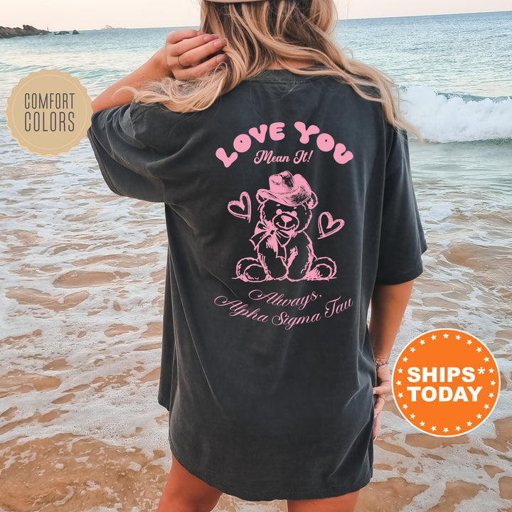 a woman standing on the beach wearing a love you shirt