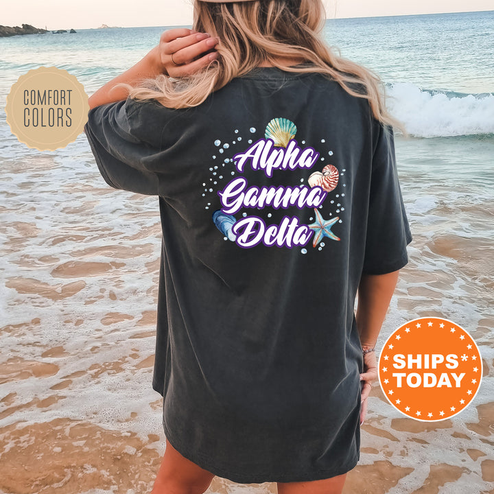 a woman standing on a beach wearing a black shirt