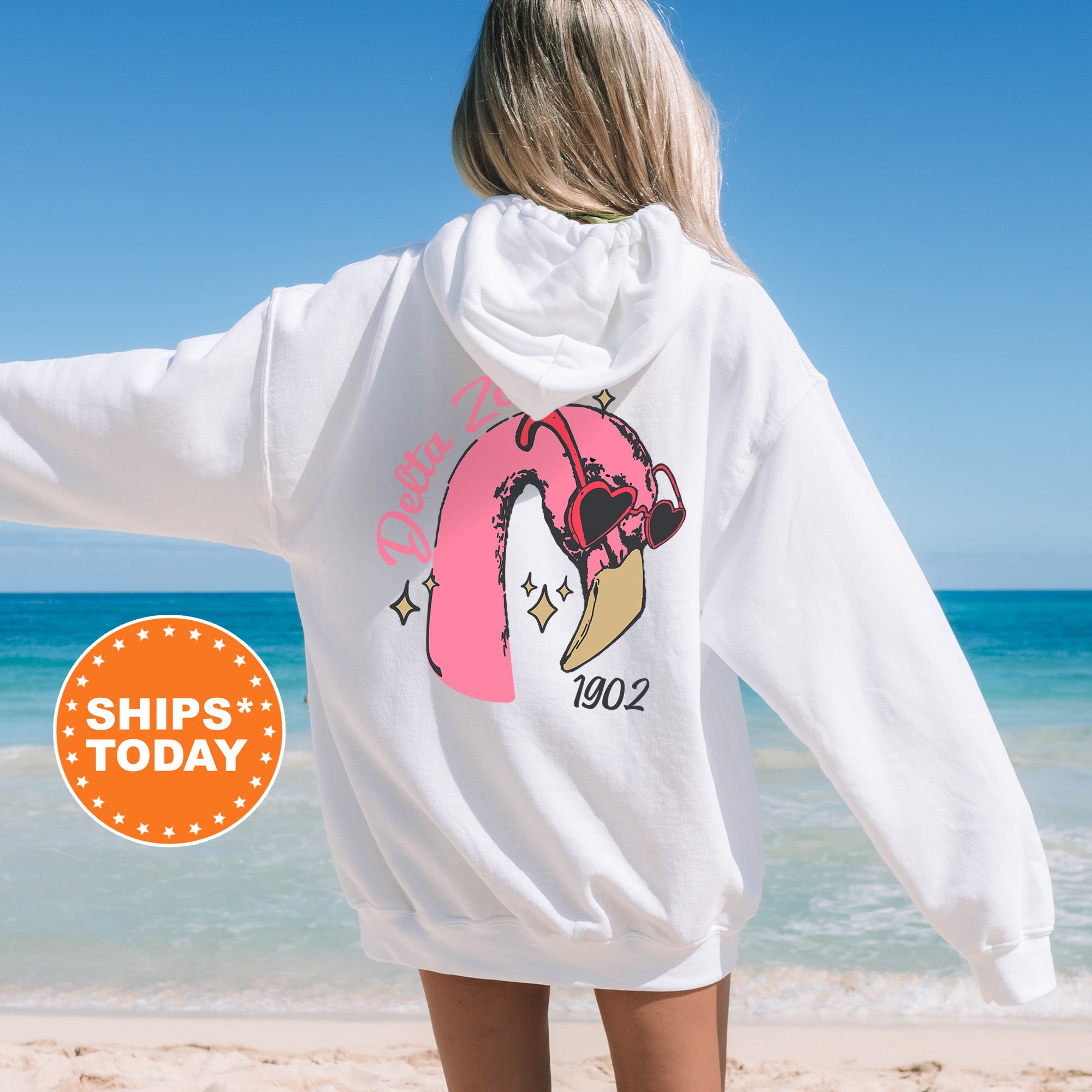 a woman standing on a beach wearing a white sweatshirt