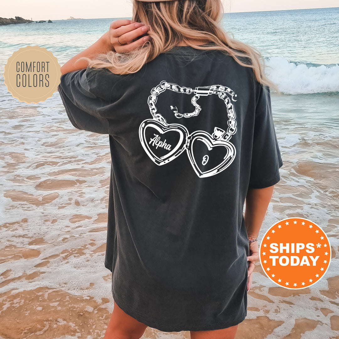 A woman wearing a black t-shirt with a graphic design on the back, standing on a beach with the ocean in the background.