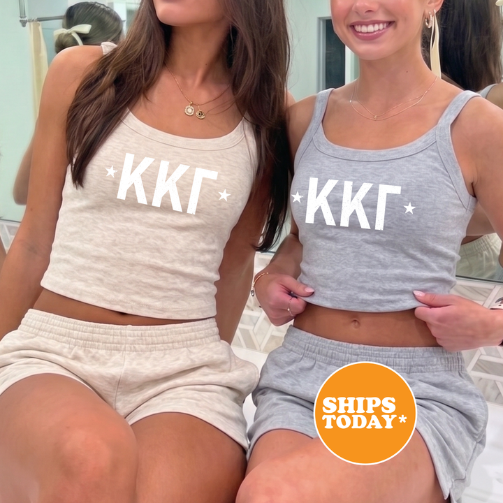 Two women wearing matching tank tops with the letters "KKT" printed on them, posing together in front of a mirror.