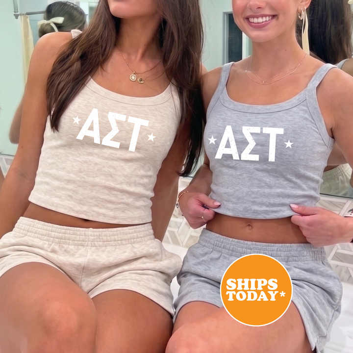 Two women wearing matching tank tops with the letters 'ΣΛΑ' printed on them, posing together in front of a mirror.