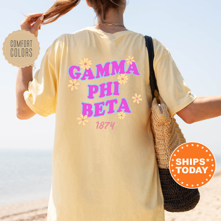 A person wearing a yellow t-shirt with the text "GAMMA PHI BETA 1874" printed on it, standing on a beach.