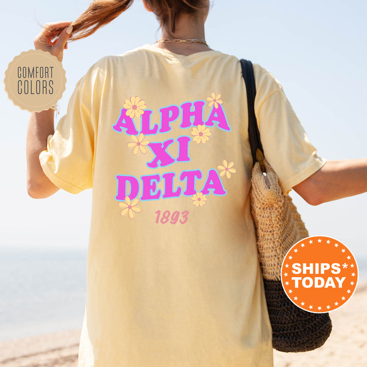 a person wearing a yellow t-shirt with the text "ALPA XI DELTA" printed on it, standing on a beach.