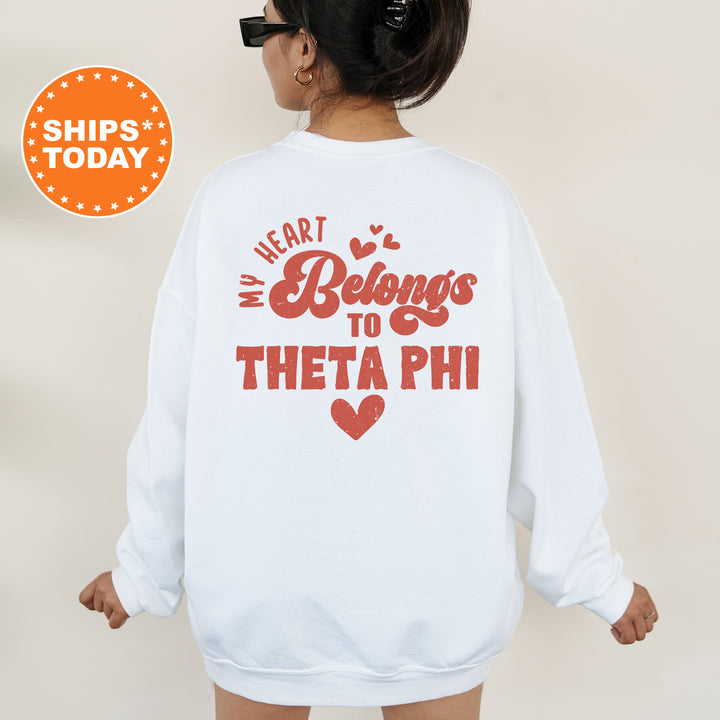 a woman wearing a white sweatshirt that says heart belongs to thea phi