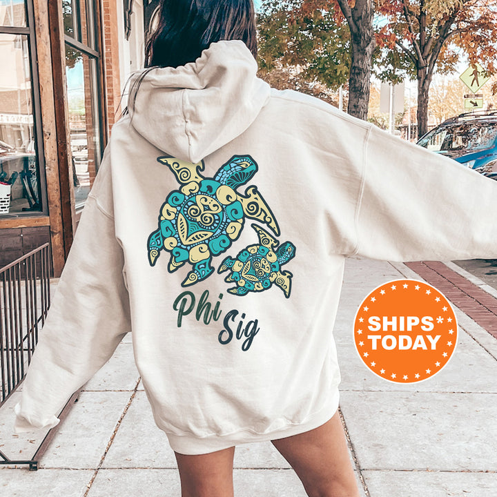 A person wearing a white hoodie with a colorful turtle design and the text "Phi Sig" printed on it, standing on a sidewalk.