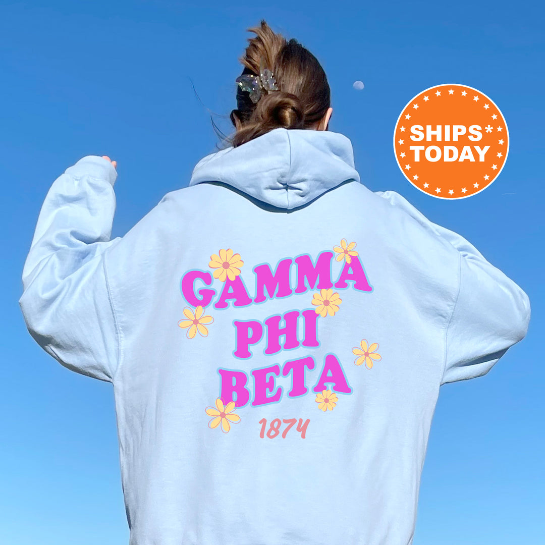 A person wearing a white hoodie with the text "GAMA PII BETA 1874" printed on it, standing against a clear blue sky.