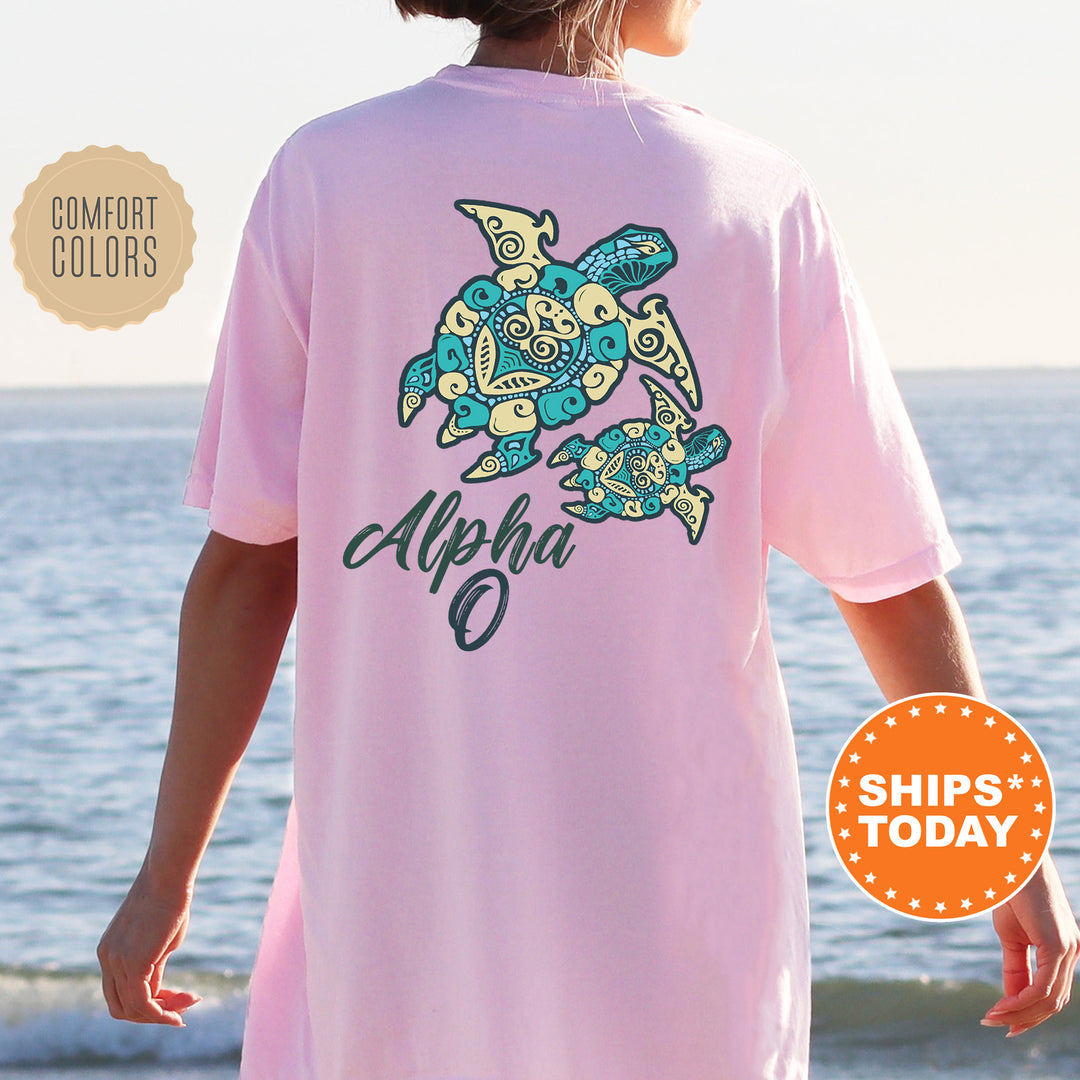 A person wearing a pink t-shirt with a graphic of a turtle and the word "Alpha" printed on it, standing near the ocean.