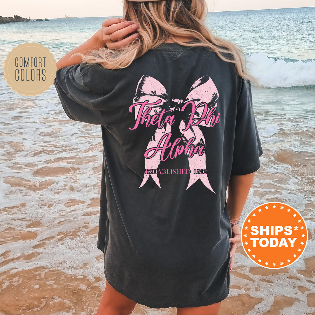 a woman standing on a beach wearing a black shirt with pink ribbon