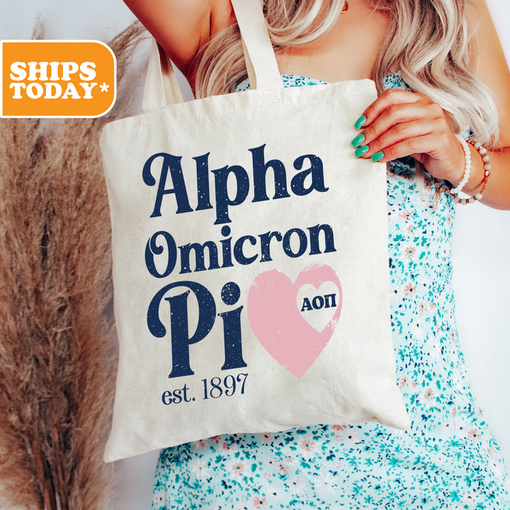 a woman holding a tote bag that says, alpha ommicron pi