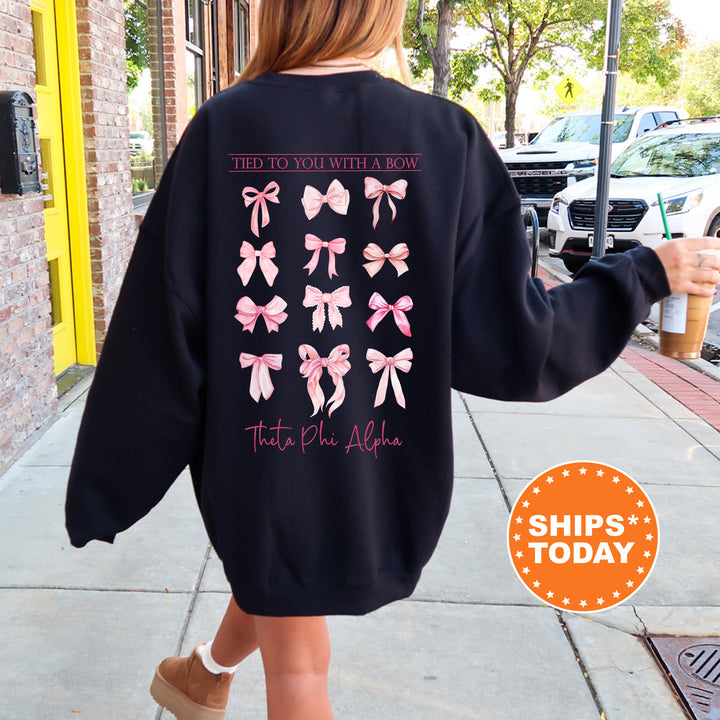 A person wearing a black sweatshirt with pink bows printed on it, walking on a sidewalk.