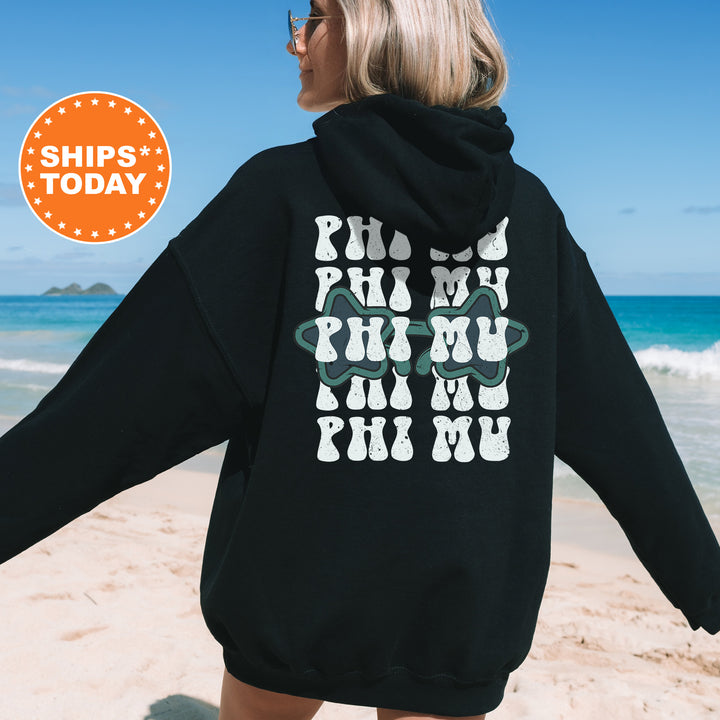a woman walking on the beach wearing a black hoodie