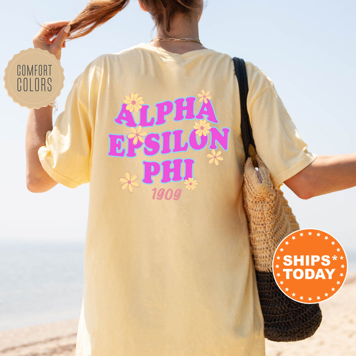 A person wearing a yellow t-shirt with the text "ALPHA EPSILON PHI" printed on it, standing on a beach.