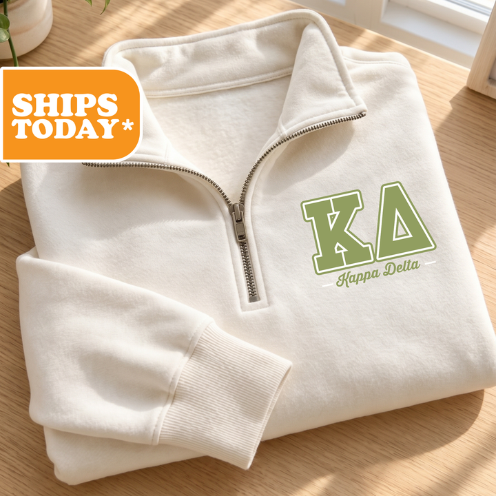 A white zip-up jacket with the Kappa Delta logo and text is displayed on a wooden surface.