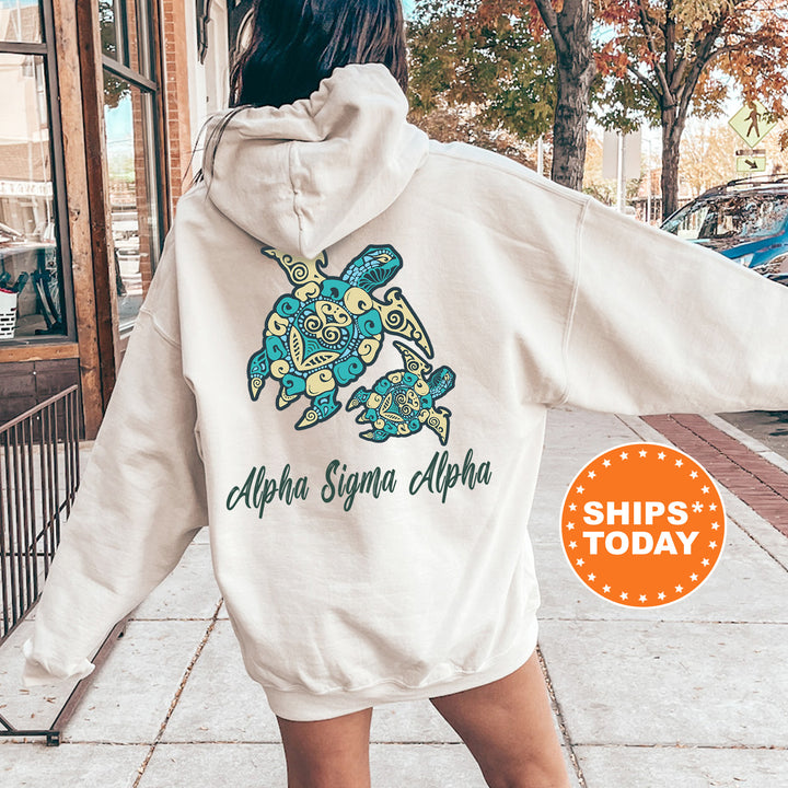 A person wearing a white hoodie with a graphic design of a turtle and the text "Alpha Sigma Alpha" printed on it, standing on a sidewalk.