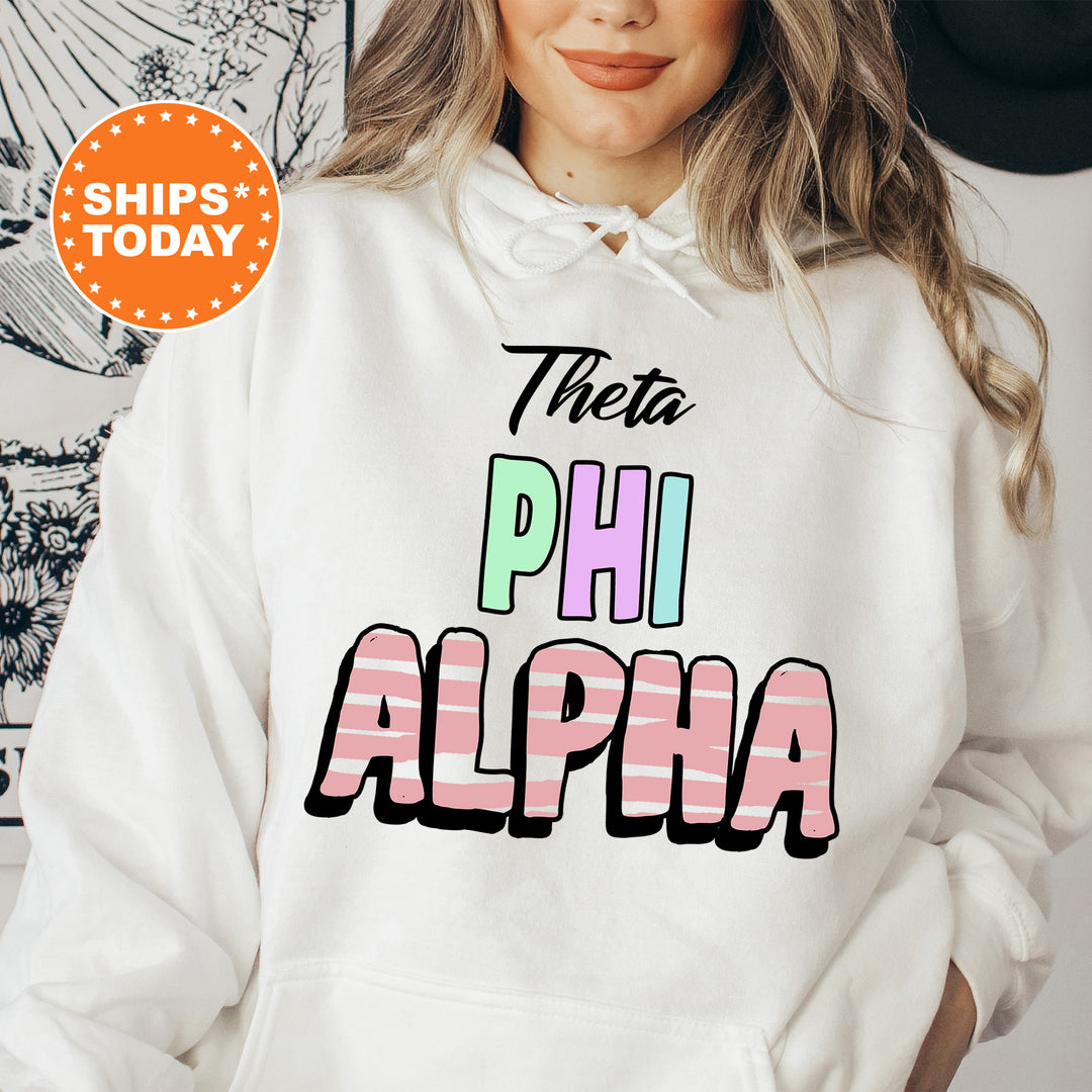 a woman wearing a white hoodie with the words thera phi alpha on