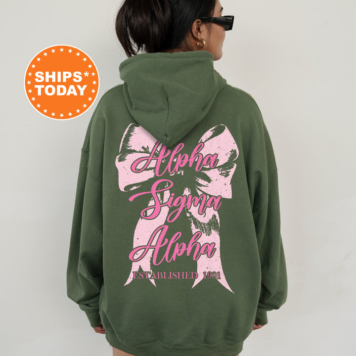 a woman wearing a green hoodie with a pink bow on it