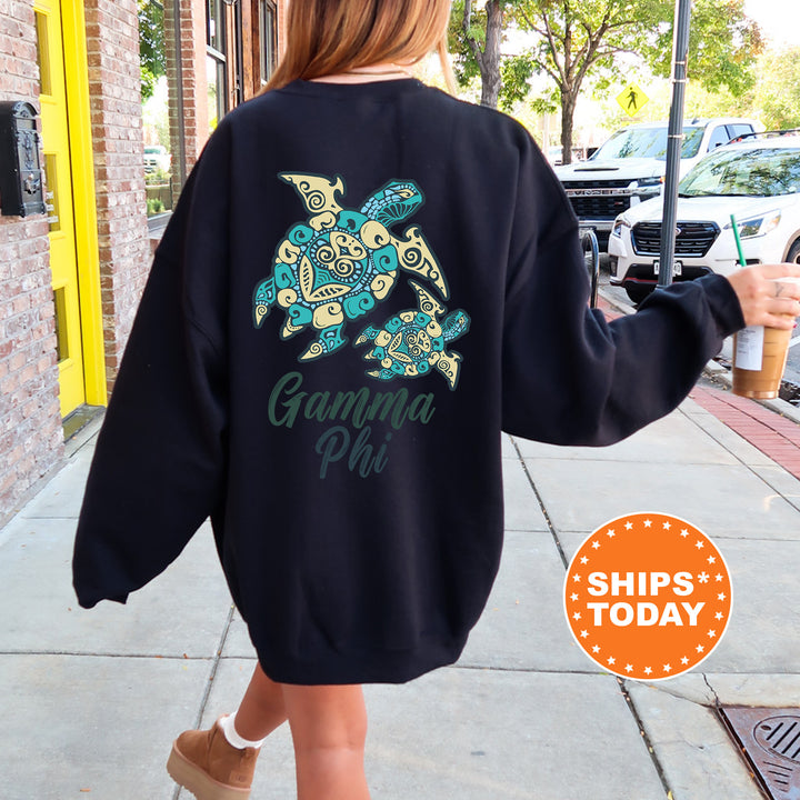 A woman wearing a black sweatshirt with a graphic of a turtle and the text "Gamma Phi" printed on it, walking down a sidewalk.
