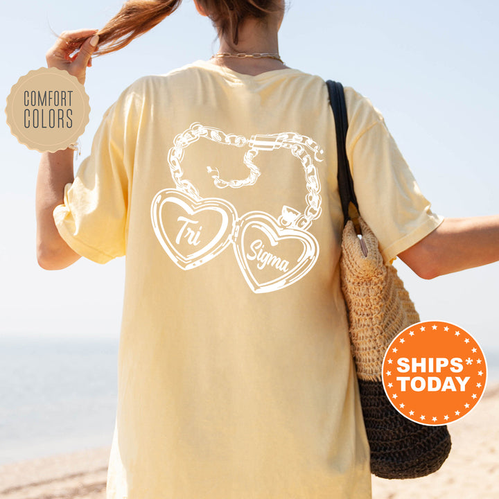 A person wearing a yellow t-shirt with a graphic design on the back, standing on a beach with a handbag and a sign that says "SHIPS TODAY".