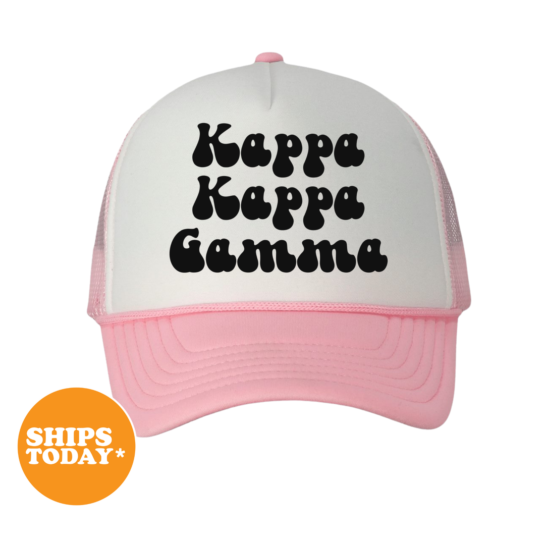 A pink and white baseball cap with the text "Kappa Kappa Gamma" printed on it.
