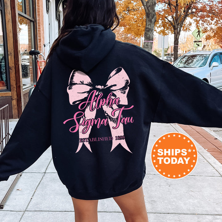 a woman in a black hoodie with a pink bow on it