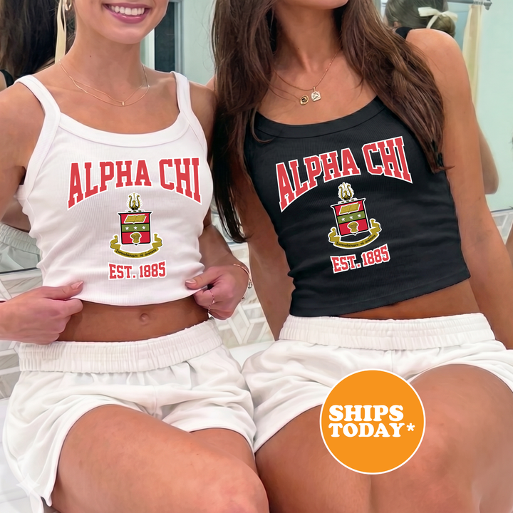Two women wearing matching white tank tops with the text "ALPA CHI" and "EST. 1895" printed on them, along with a crest design.