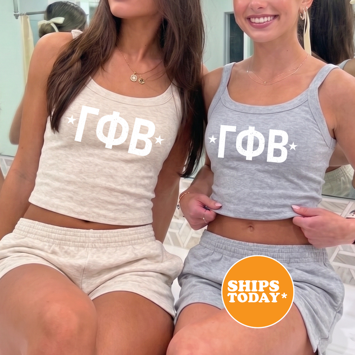 Two women wearing matching tank tops with the Greek letters "ΦΑΓ" printed on them, posing together in front of a mirror.