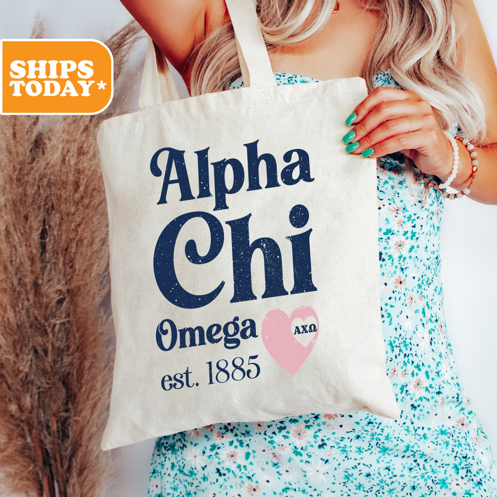a woman holding a tote bag that says alpha chi omega