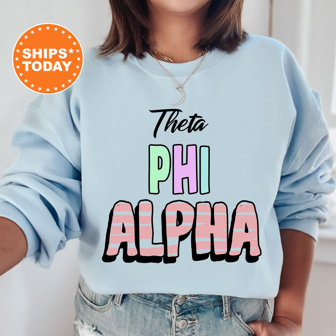 a woman wearing a blue sweatshirt with the words, thea, phi, and